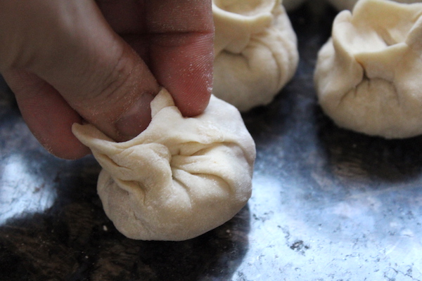 Pinching dough with beef inside to form dumpling shape