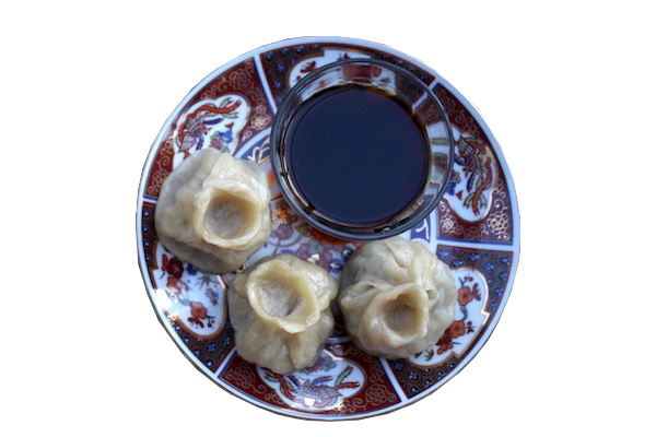 Buuz (A Mongolian Dumpling on a plate next to some soy sauce)